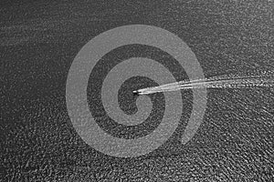 Boat on lake cruising over rippled water minimalist black and white view.