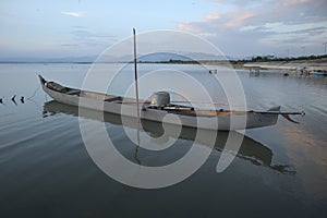 Boat in the lake at sunset. Rowing boat floating over the Limboto Lake waters. Gorontalo, Indonesia