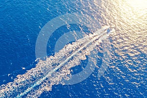 Boat launch at high speed floats to sunlight in the Mediterranean, aerial top view