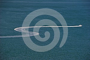 Boat leaving a white 'S' shaped trail on the sea water surface