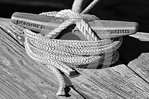 A Boat Line Fasted around a Cleat on a Wooden Dock.