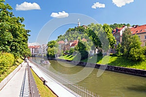 Boat on Ljubljanica river and castle raising above on the hilltop, Ljubljana, Slovenia photo