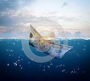 Boat made of dollar banknote are sinking in the ocean