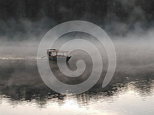 A boat in the middle misty lake in the morning