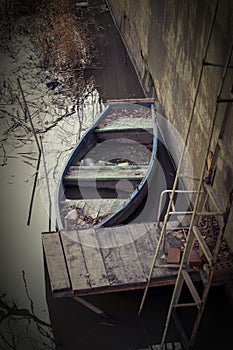 The boat is moored in the canal by the pier