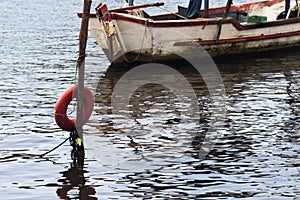 Boat moored at the coast with red buoy and reflection in the water