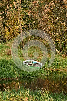 A boat moored to the river bank in the reeds on a sunny, calm day. Summer