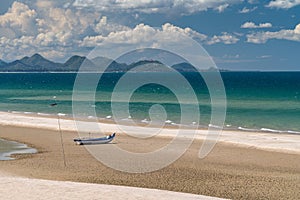 The boat moored on the white sand beach.