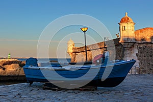 Boat near medieval Forte de Bandeira at sunset in Portugal photo