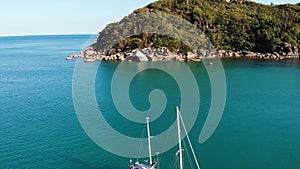 Boat near tropical shore. Amazing drone view of modern yacht sailing on calm sea water near coast of tropical volcanic