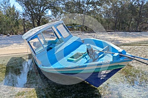 A boat parked next to the shore on Gili Meno, Lombok, Indonesia. Small fishing boat parked and moored on the beach at low tide.