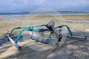 A boat parked next to the shore on Gili Meno, Lombok, Indonesia. Small fishing boat parked and moored on the beach at low tide.