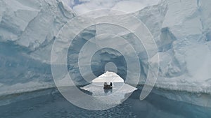Boat passes through iceberg arch. Antarctica.