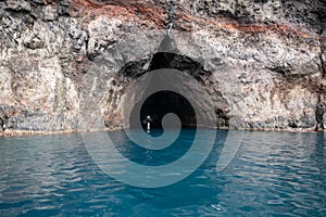 Boat passes through the rock tunnel washed out by the surf, Oki Islands, Shimane, Japan, Unesco Global Geopark.