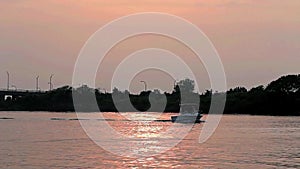 Boat passing Captree State Boat Basin during sunset in the State Channel.