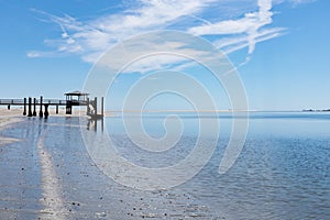Boat pier at the estuary of Tybee Creek and the Atlantic ocean, blue sky with clouds reflected in the still waters