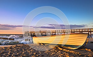 A boat and a pier during sunset over the Baltic Sea