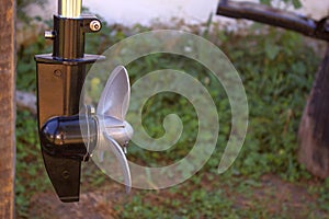 Boat propeller engine element on a green backyard background.