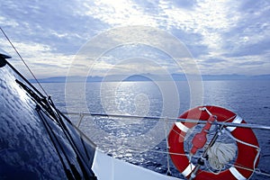 Boat rail with round orange lifesaver blue sea