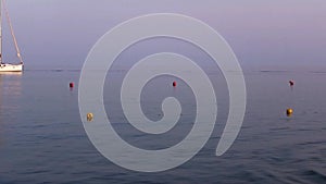 A boat reaching a moored sailboat at sunset.