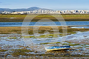 Boat by Ria Formosa wetlands with Faro in the background, Algarve, Portugal