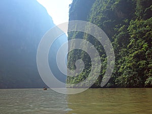 A boat rides down the Sumidero Canyon as sunlight bursts through in the morning in Chiapas State