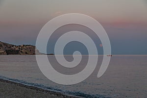 A boat and a rising moon in a Mediterranean beach of Ionian Sea - Bova Marina, Calabria, Italy