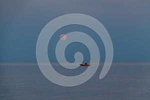 A boat and a rising moon in a Mediterranean beach of Ionian Sea - Bova Marina, Calabria, Italy