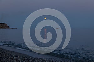 A boat and a rising moon in a Mediterranean beach of Ionian Sea - Bova Marina, Calabria, Italy