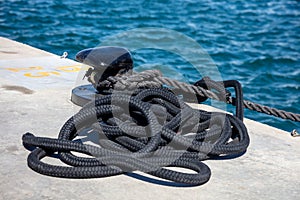 Boat ropes on black mooring bollard, luxury yachts marina pier