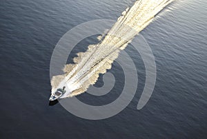 Boat  rushing along a blue water surface, top view