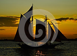 Boat sailing against crimson sunset - saturated silhouette