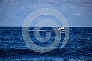 Boat sailing in the calm blue waters of the Atlantic Ocean towards Inis Oirr Island