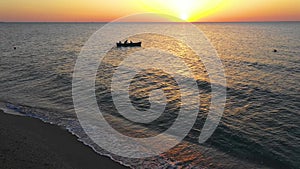 A boat sailing on the sea, early in the morning, beautiful sunrise as background. Aerial view Seascape. Local people fishing on a