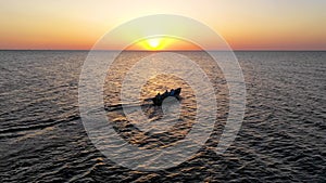 A boat sailing on the sea, early in the morning, beautiful sunrise as background. Aerial view Seascape. Local people fishing on a