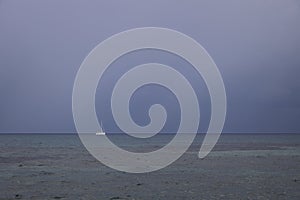 Boat sailing in the upcomming storm. Sailboat in bad weather sail at opened sea. Sailing yacht under heavy cloud sky.