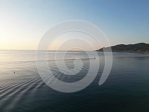 a boat sailing on the water with a sunrise and the coast in the background