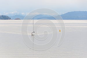 Boat sailing on a windless lake with cloudy blue sky