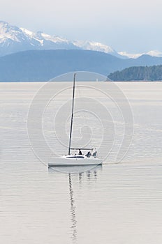 Boat sailing on a windless lake with cloudy sky