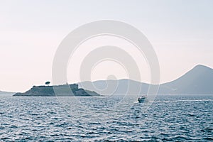 Boat sails along the Kotor Bay against the backdrop of Mamula Island. Montenegro