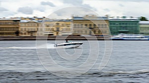 The boat sails along the river at high speed, against the background of the city`s historical buildings
