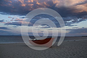 Boat on sand beach on cloudy evening sky. Fishing boat at sea shore after sunset. Summer vacation on sea. Fishing and