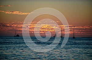 Boat on sea at sunset. Sailboats with sails. Ocean yacht along water.