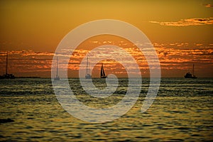 Boat on the sea at sunset. Sailboats with sails. Ocean yacht sailing in ocean water.