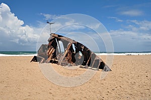 boat ship skeleton grunge half buried in brown sand in La Pedrera, Rocha, Uruguay photo