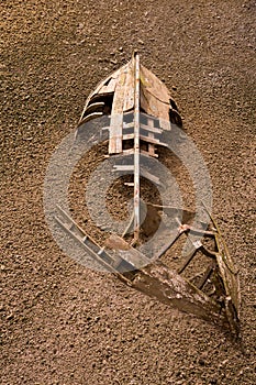 Boat ship skeleton half buried in sand