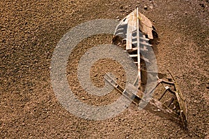 Boat ship skeleton half buried in sand