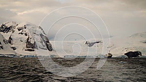 Boat in snow covered mountain landscape in Antarctica around Cuverville Island.