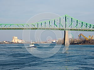 Boat on St-Lawrence river with the Jacques-Cartier bridge in background. Winter time