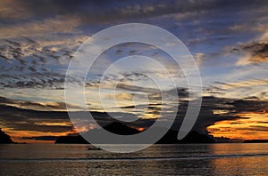 Boat at sunset behind island and clouds, Pasumpahan island, West Sumatra, Indonesia